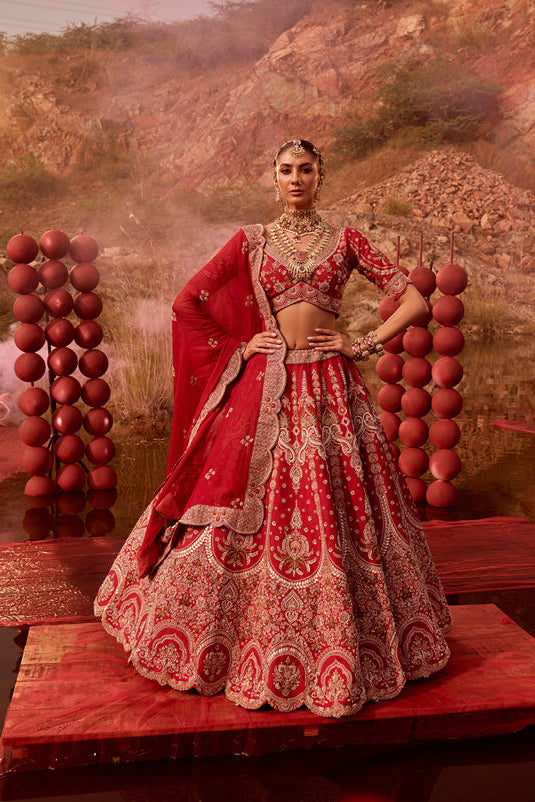 Woman in a red and gold traditional outfit standing in a scenic outdoor setting with balloons.