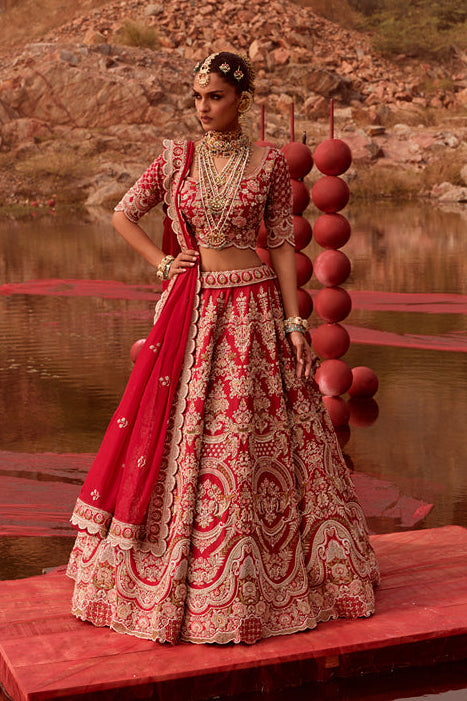 Woman in traditional red and white outfit standing on a red platform with a natural landscape in the background