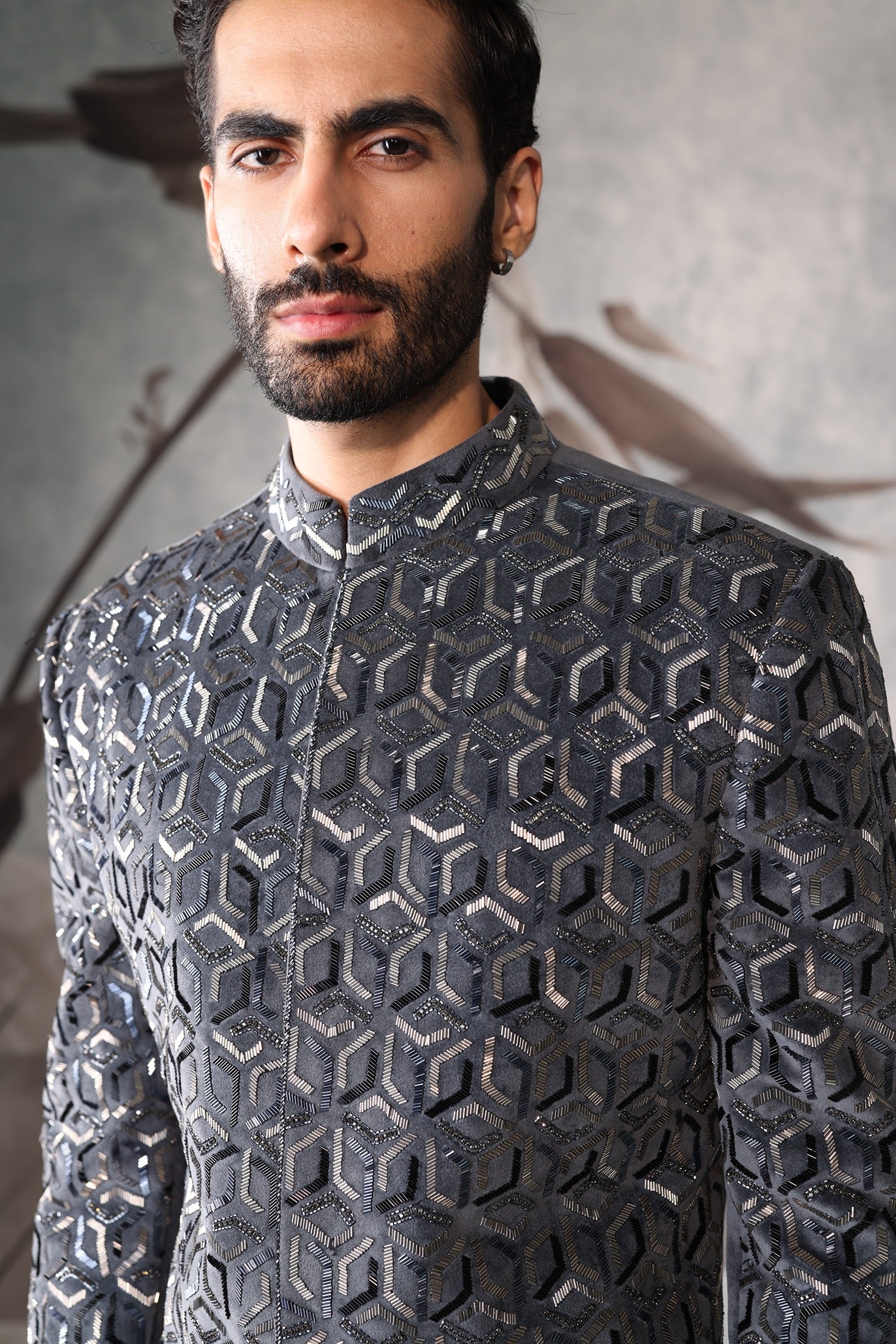 Man wearing a gray geometric patterned shirt against a neutral background