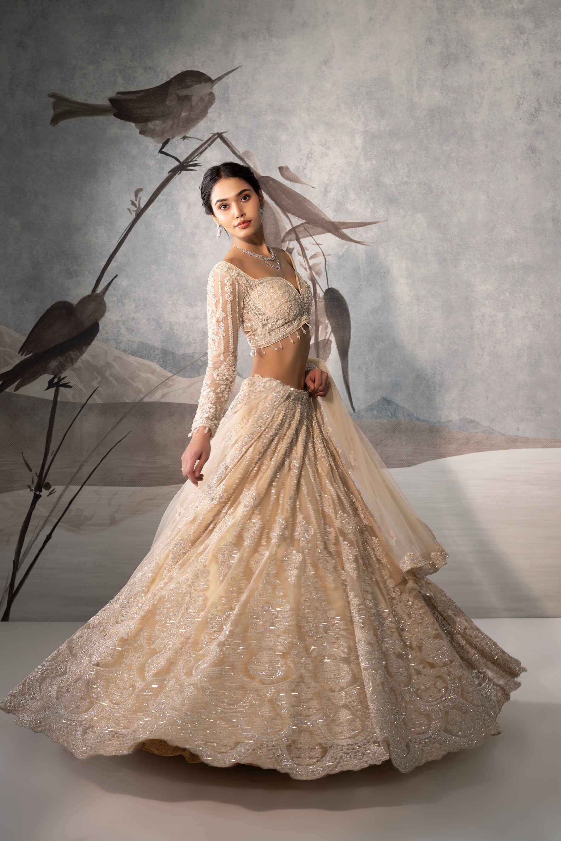 Woman in an elegant beige embroidered dress with birds on a branch in the background