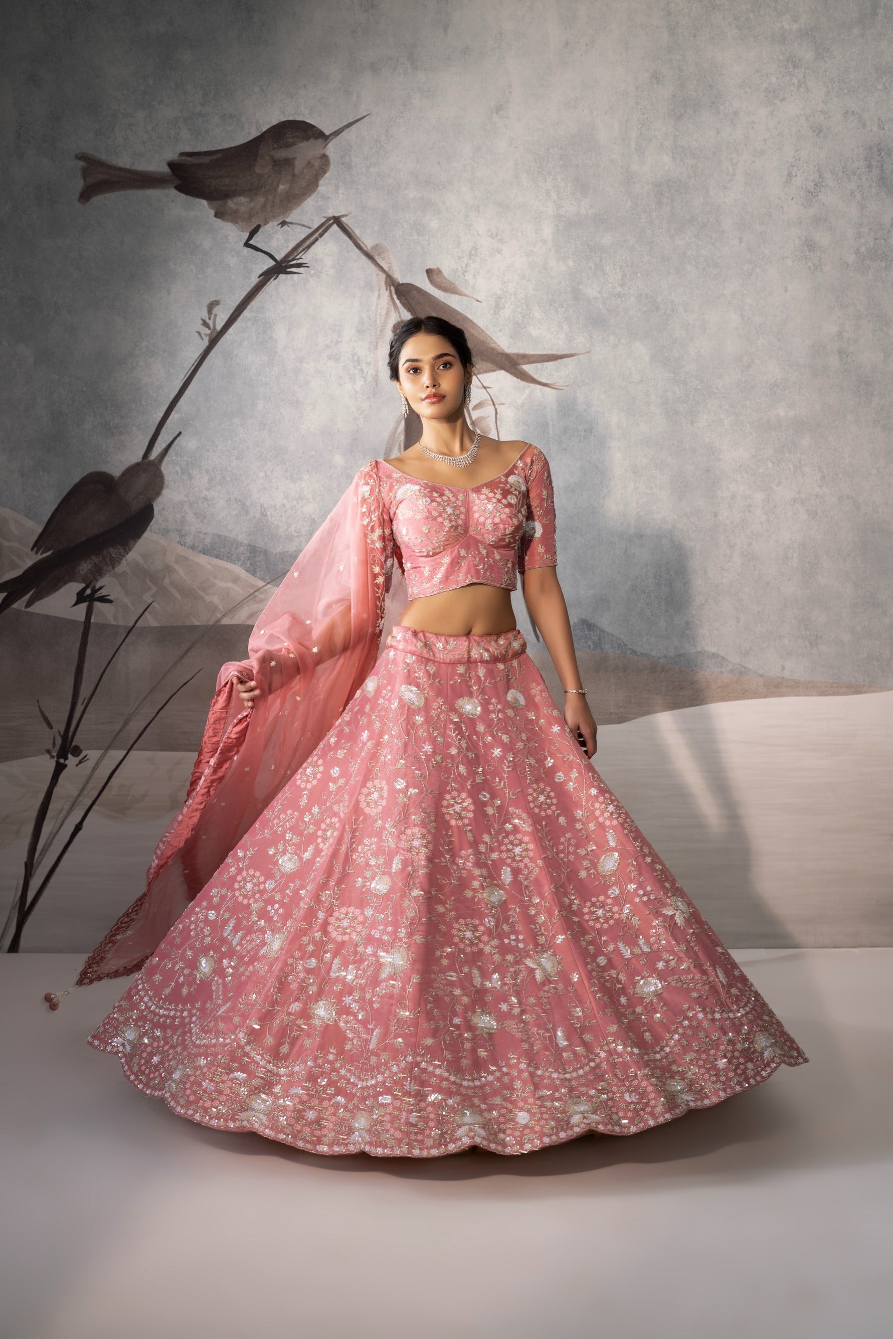 Woman in a pink traditional outfit with birds on a branch in the background