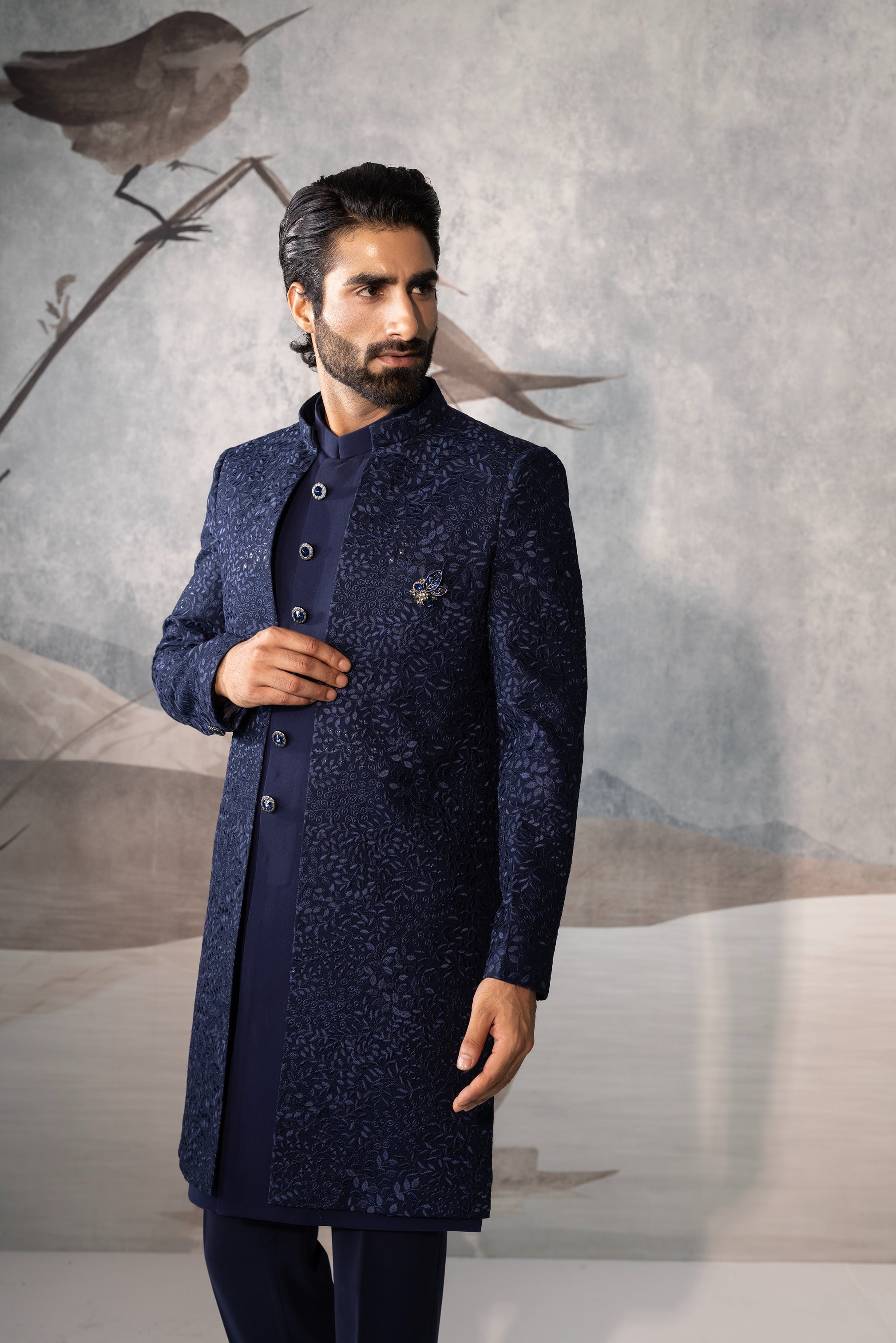 Man wearing a dark blue sherwani against a neutral background