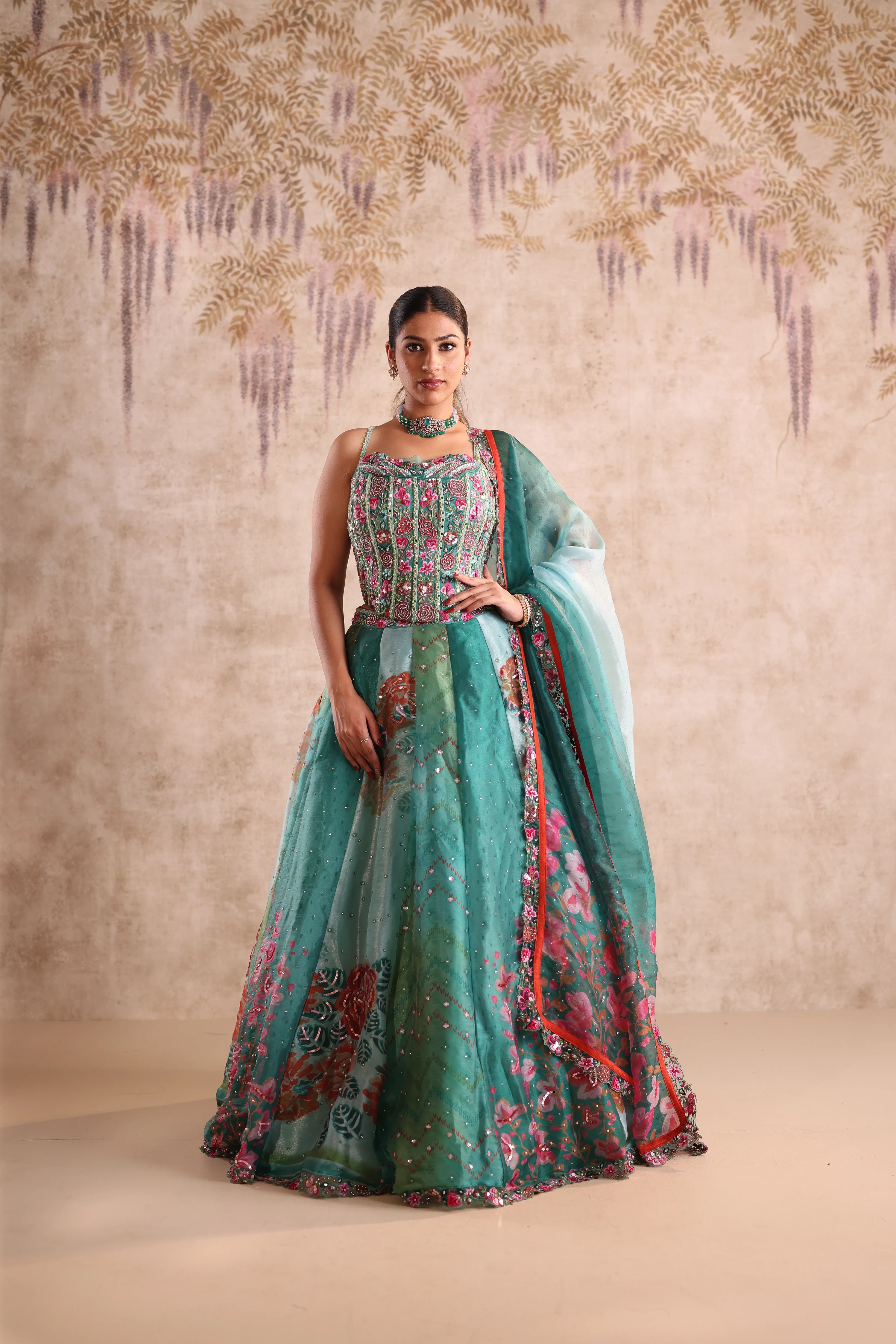 Woman wearing a traditional outfit with a floral design against a textured beige background