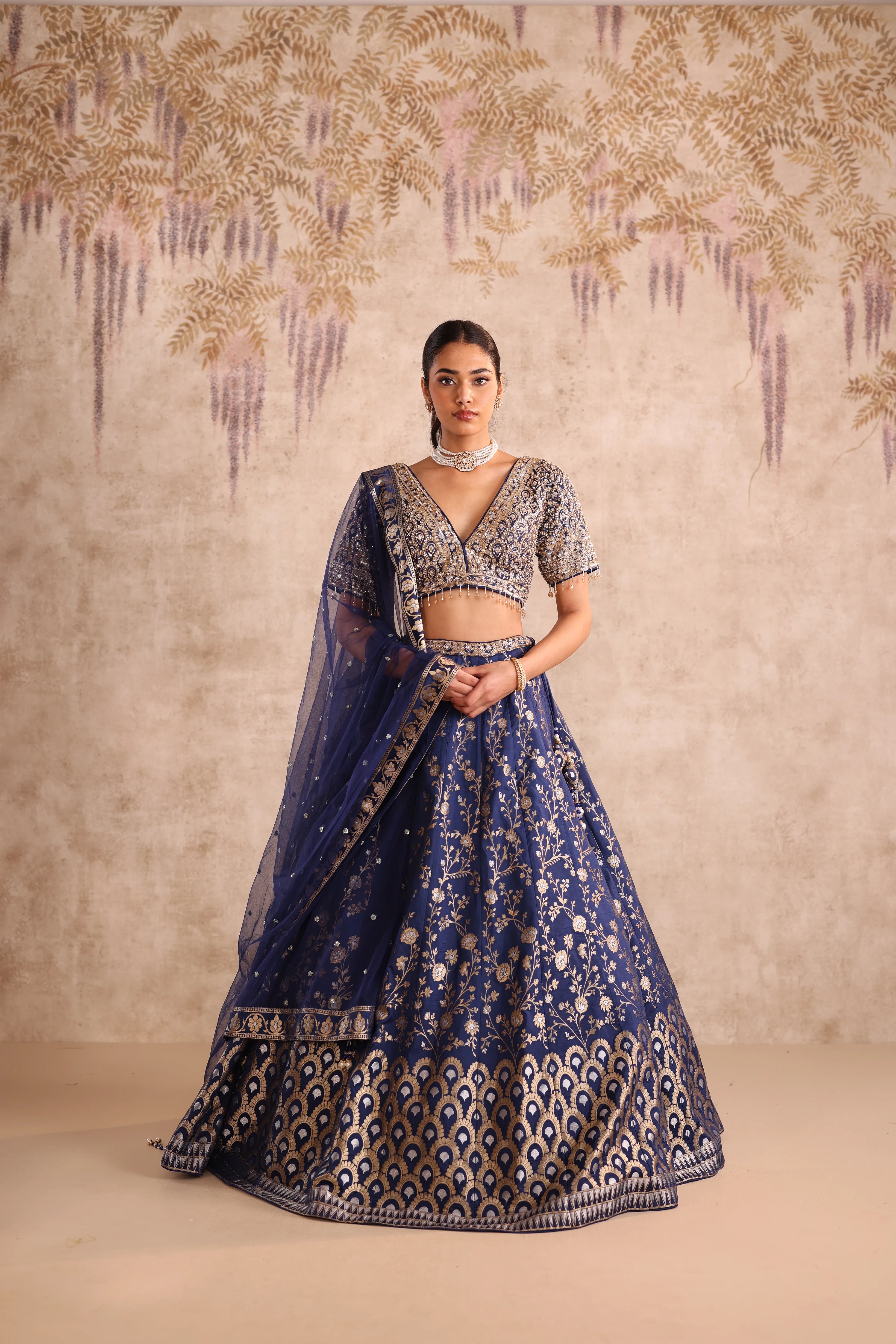 Woman in a traditional blue and silver lehenga with a decorative background