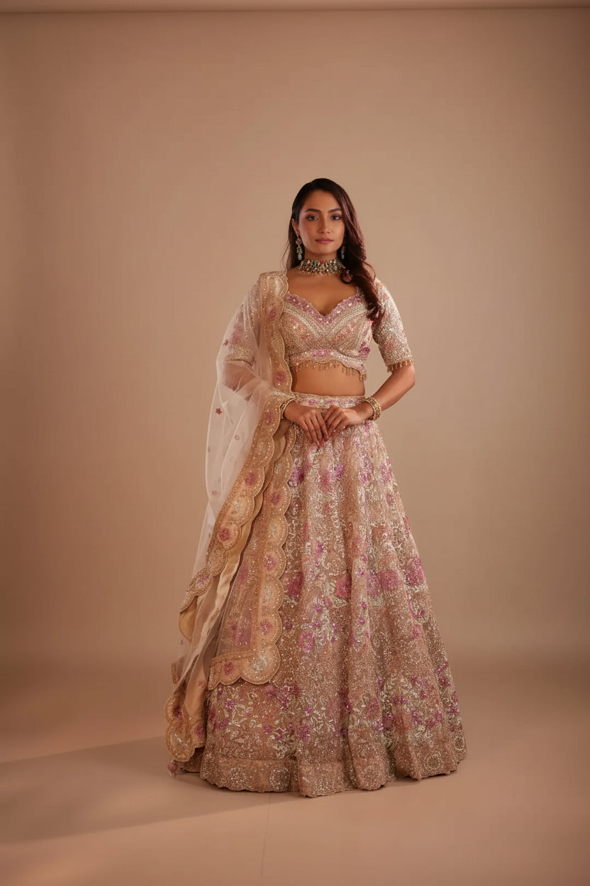 Woman in a floral lehenga standing against a textured wall.