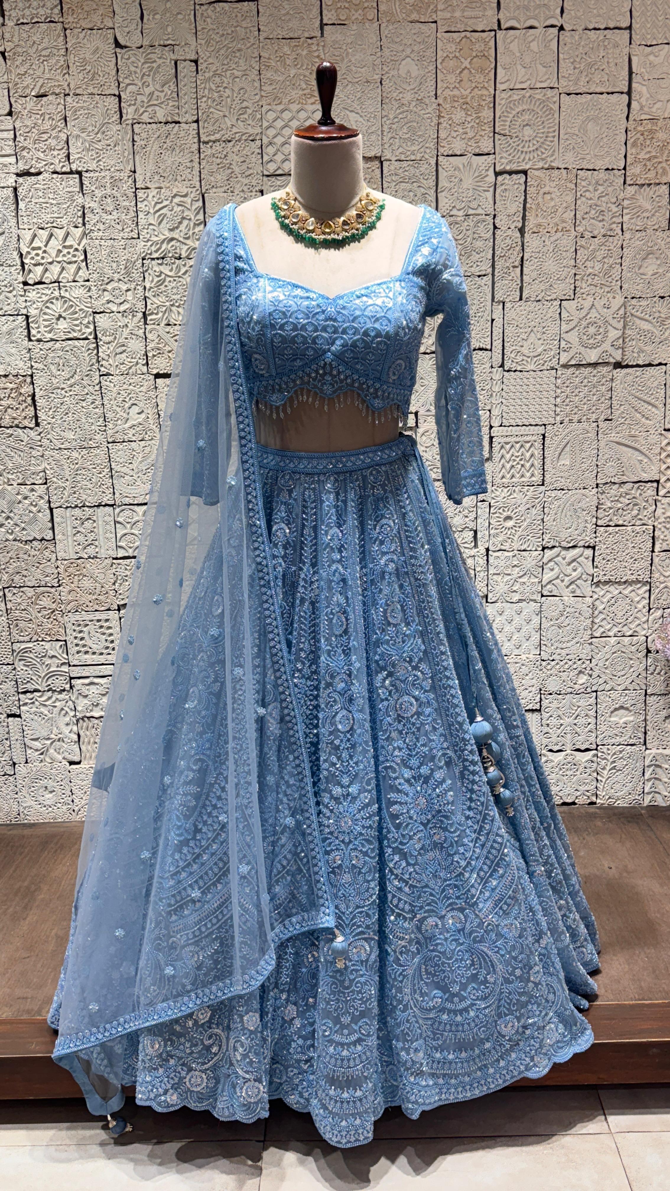 A mannequin displaying a pastel blue lehenga with zig-zag embroidery, paired with a matching blouse and dupatta with subtle borders.