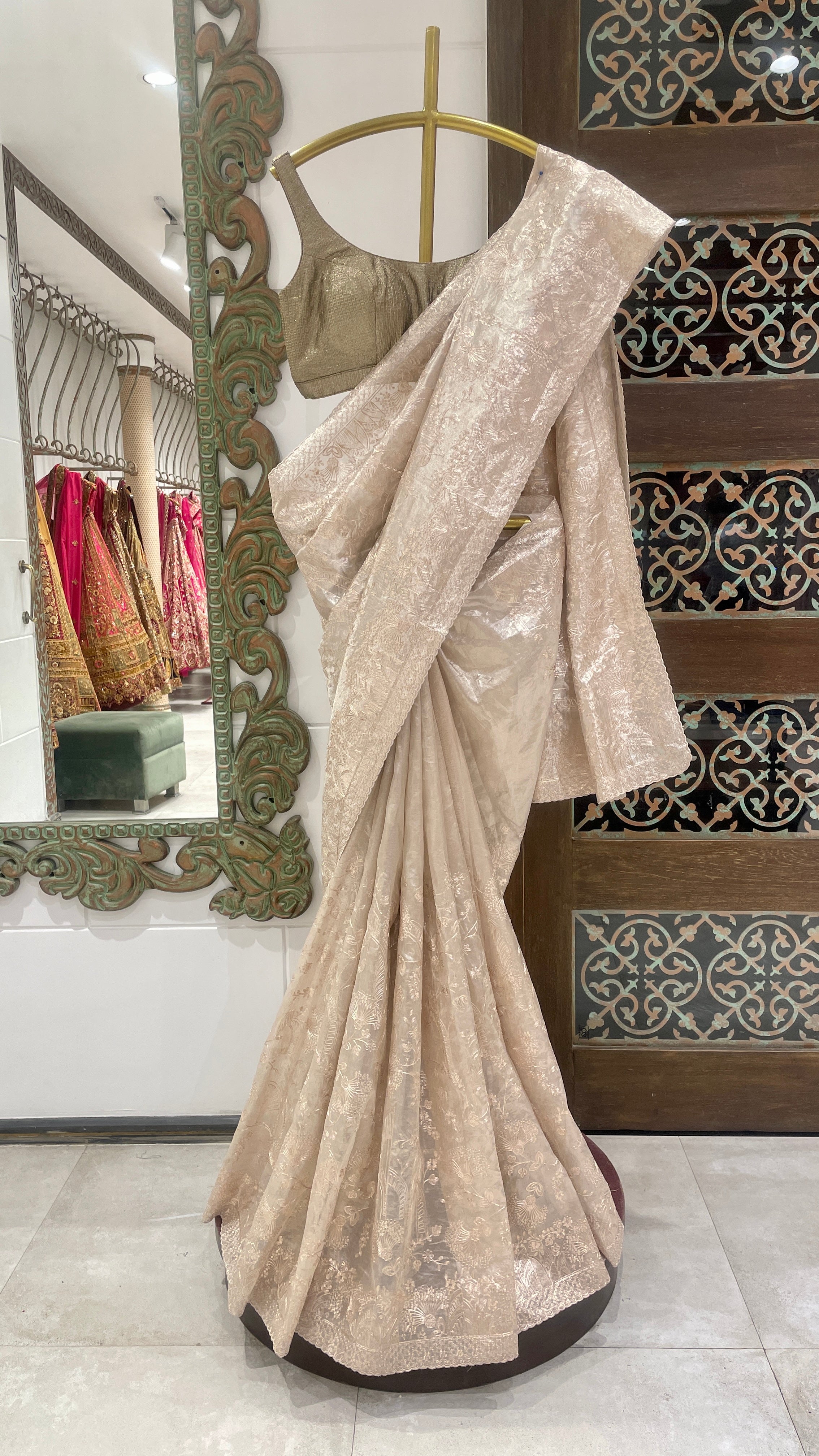 An ivory tissue saree with gold zariwork and pitta work displayed on a mannequin in a store.