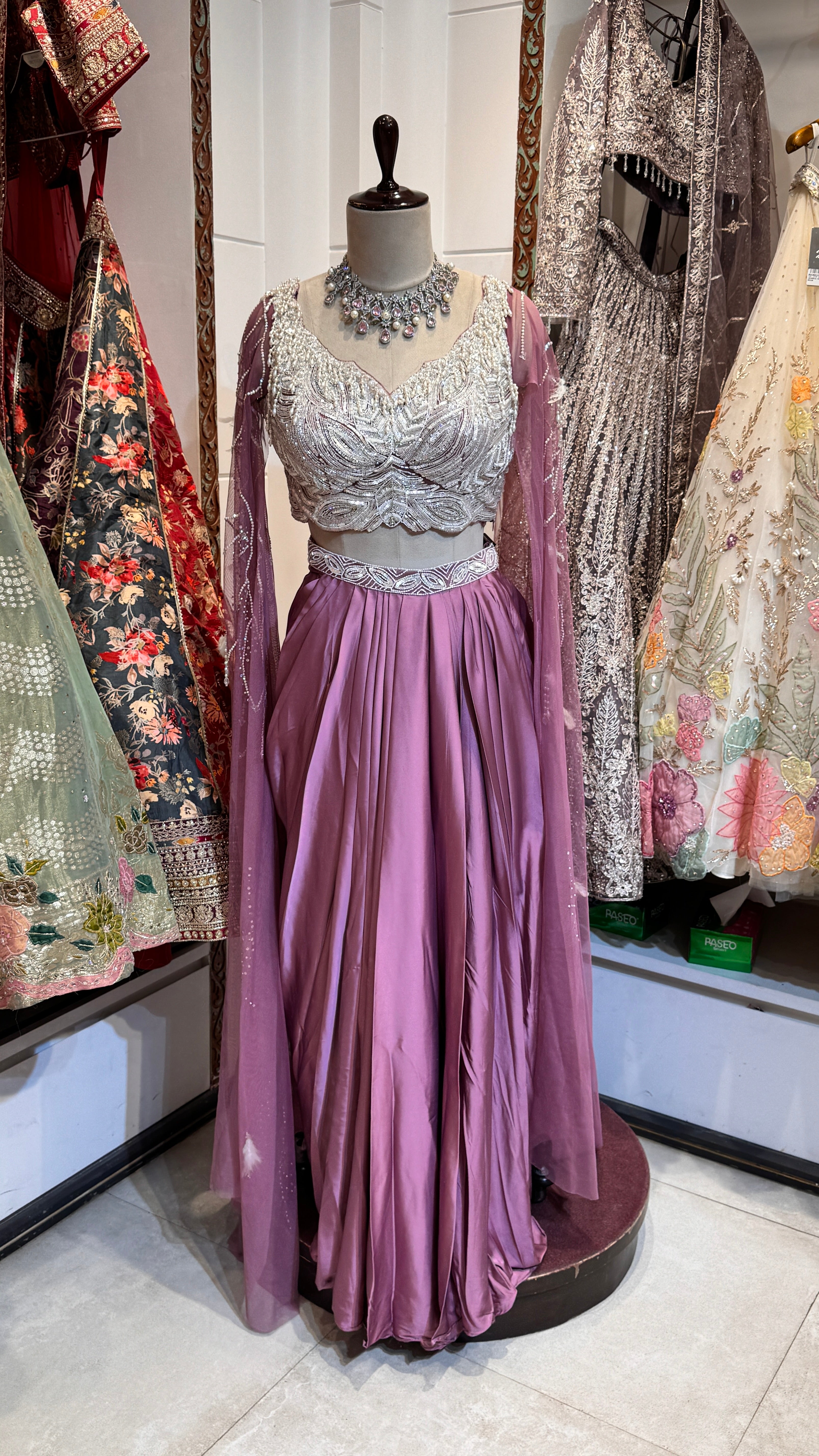 A mannequin displaying a classic pink lehenga with embroidery and a matching blouse, paired with a sheer dupatta with embroidered borders.