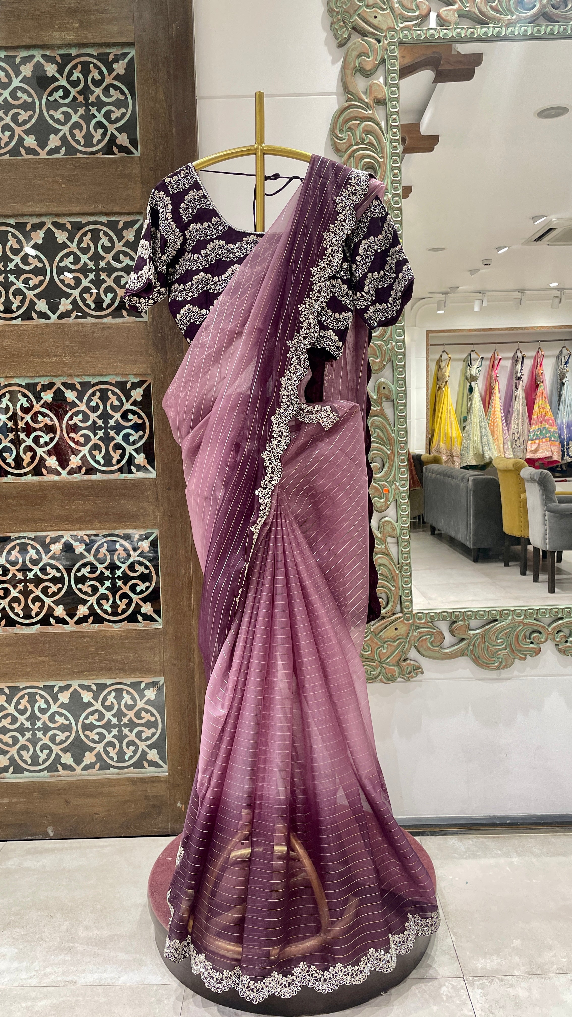 A purple ombre organza saree with embellishments displayed on a mannequin, with intricate border and pallu details.