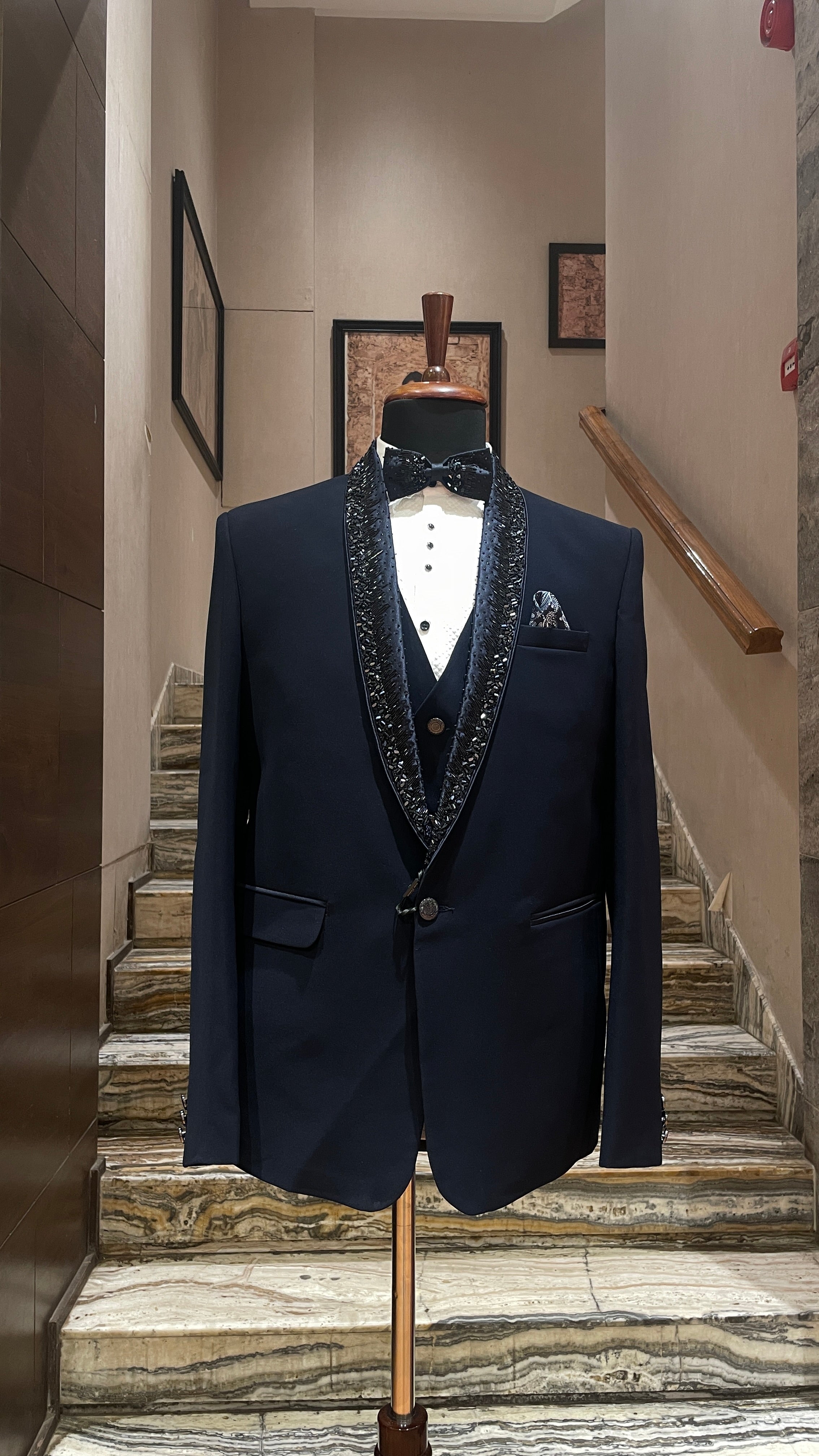 Navy blue suit with decorative lapels on a mannequin against a staircase background