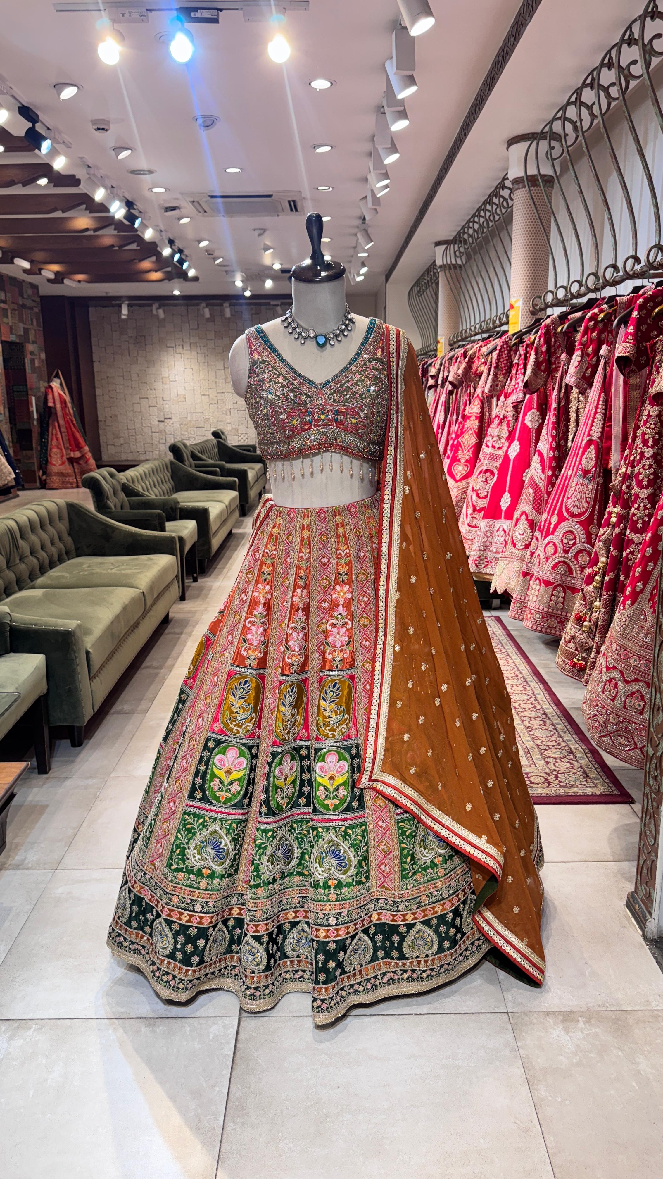 Traditional embroidered lehenga on a mannequin in a store setting with other clothing and decor.