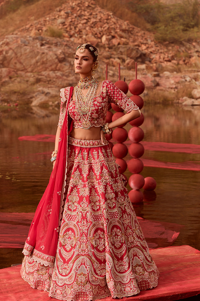 Woman in a red and white traditional outfit standing by a lake with decorative balloons.
