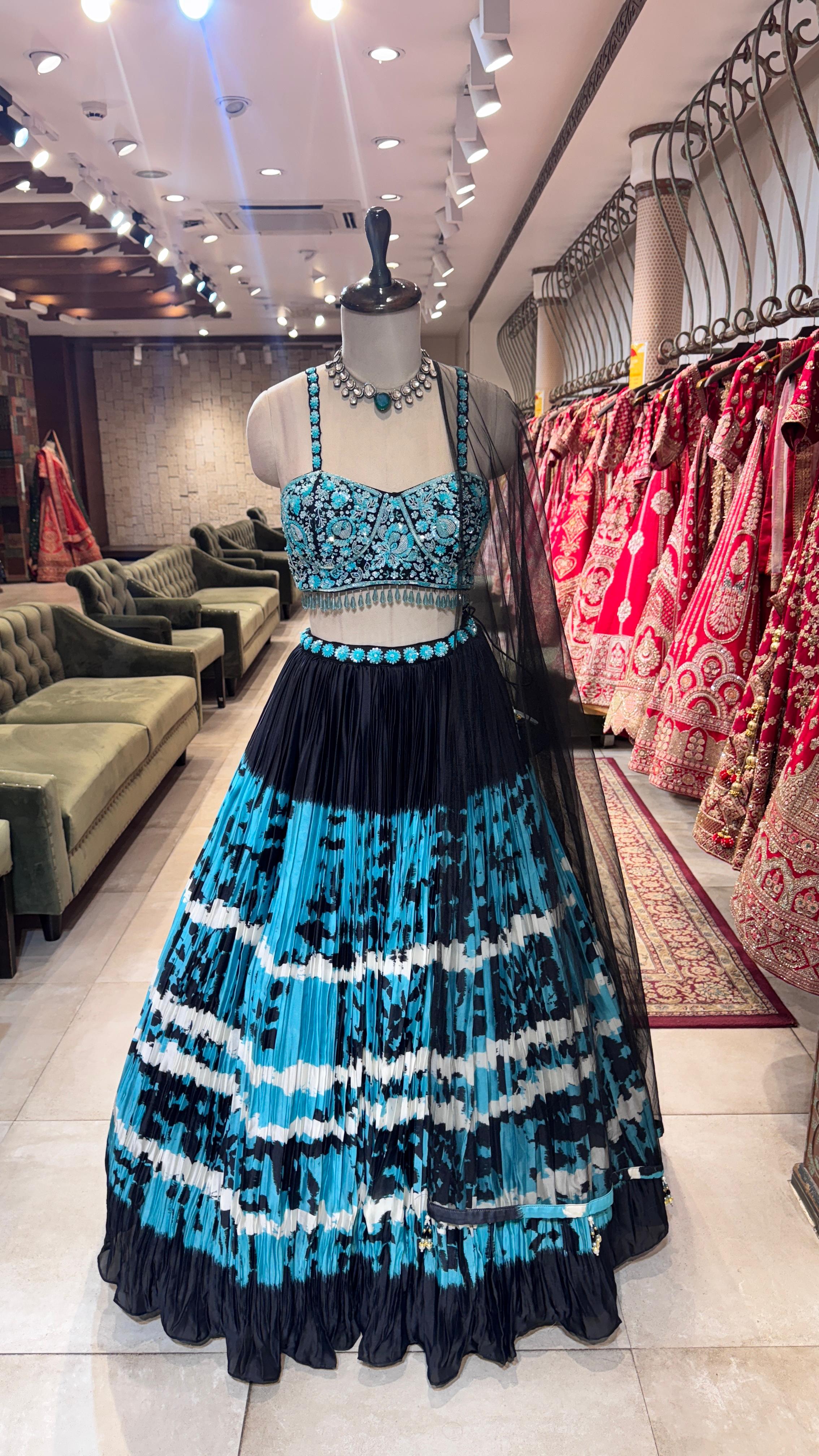 Mannequin wearing a blue and black dress in a store setting with other clothing in the background.