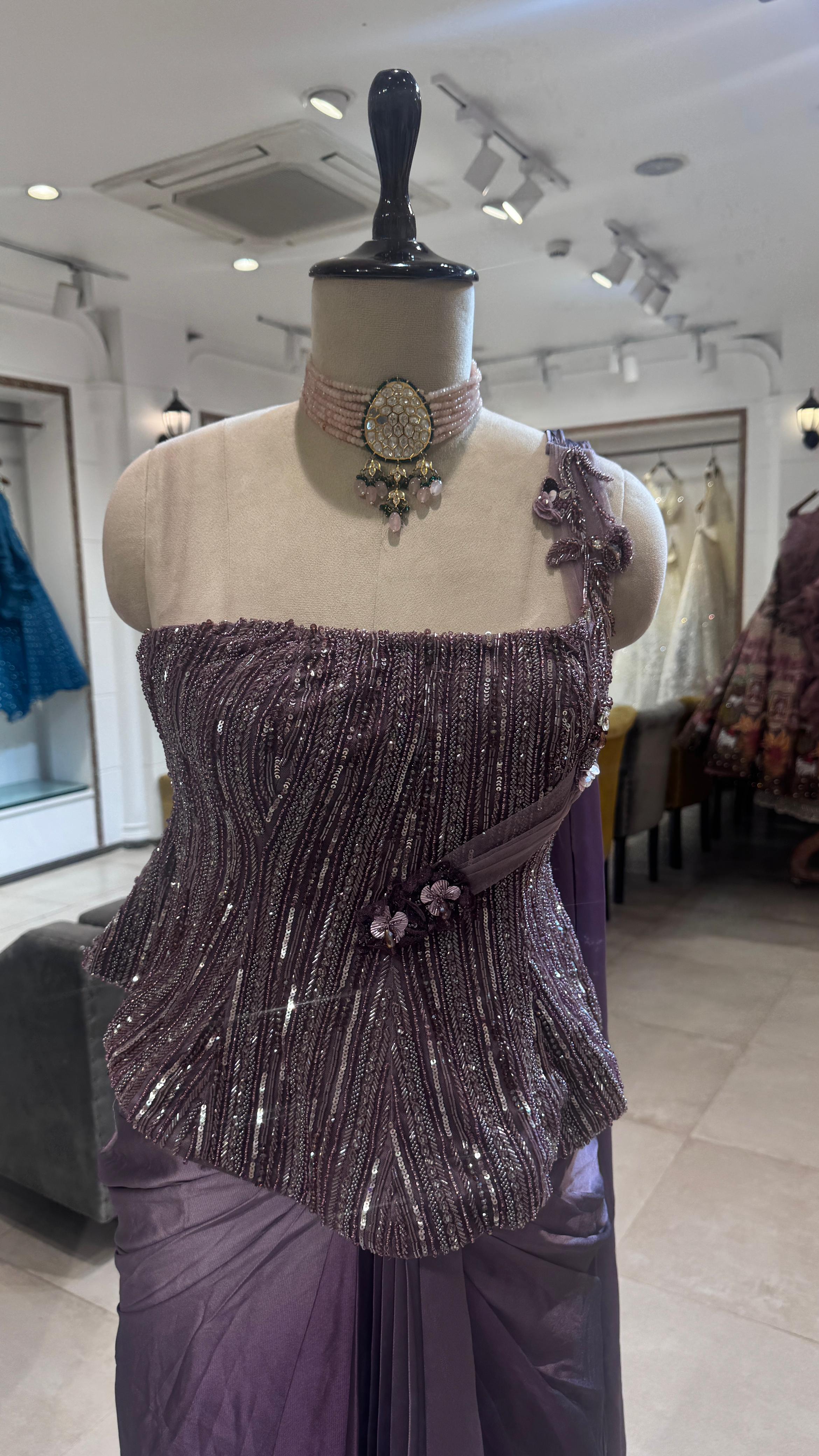 Mannequin wearing a purple beaded dress in a store setting