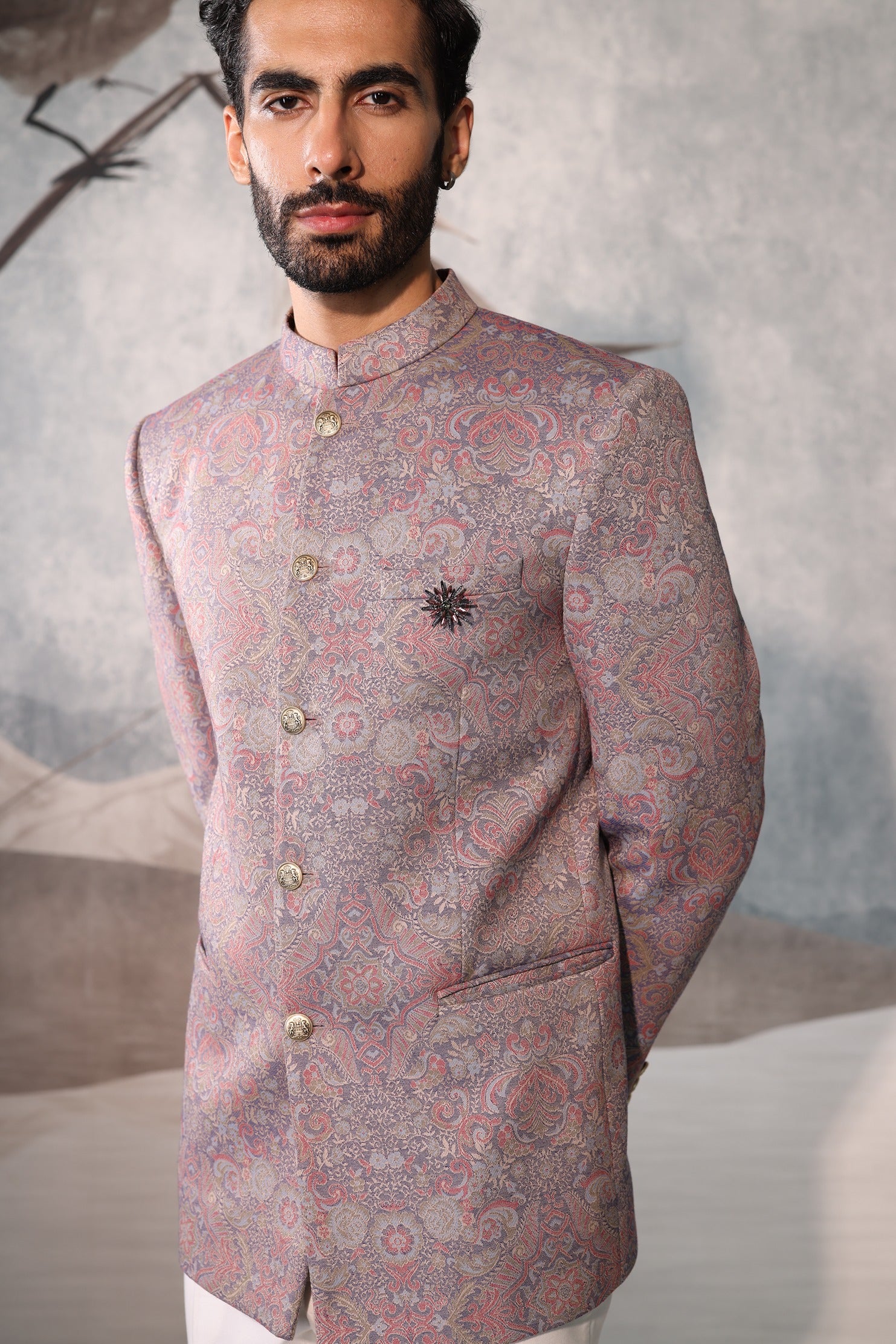 Man wearing a patterned traditional outfit against a neutral background