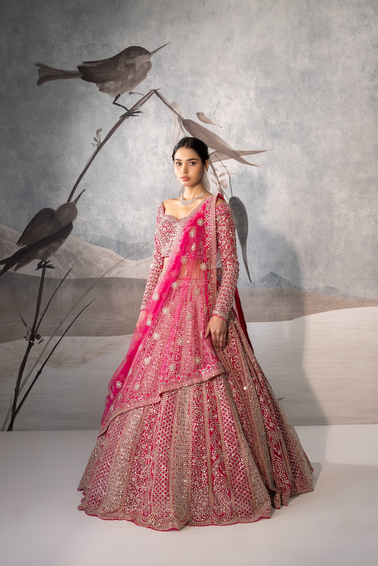 Woman in a pink and gold traditional outfit with birds on a branch in the background