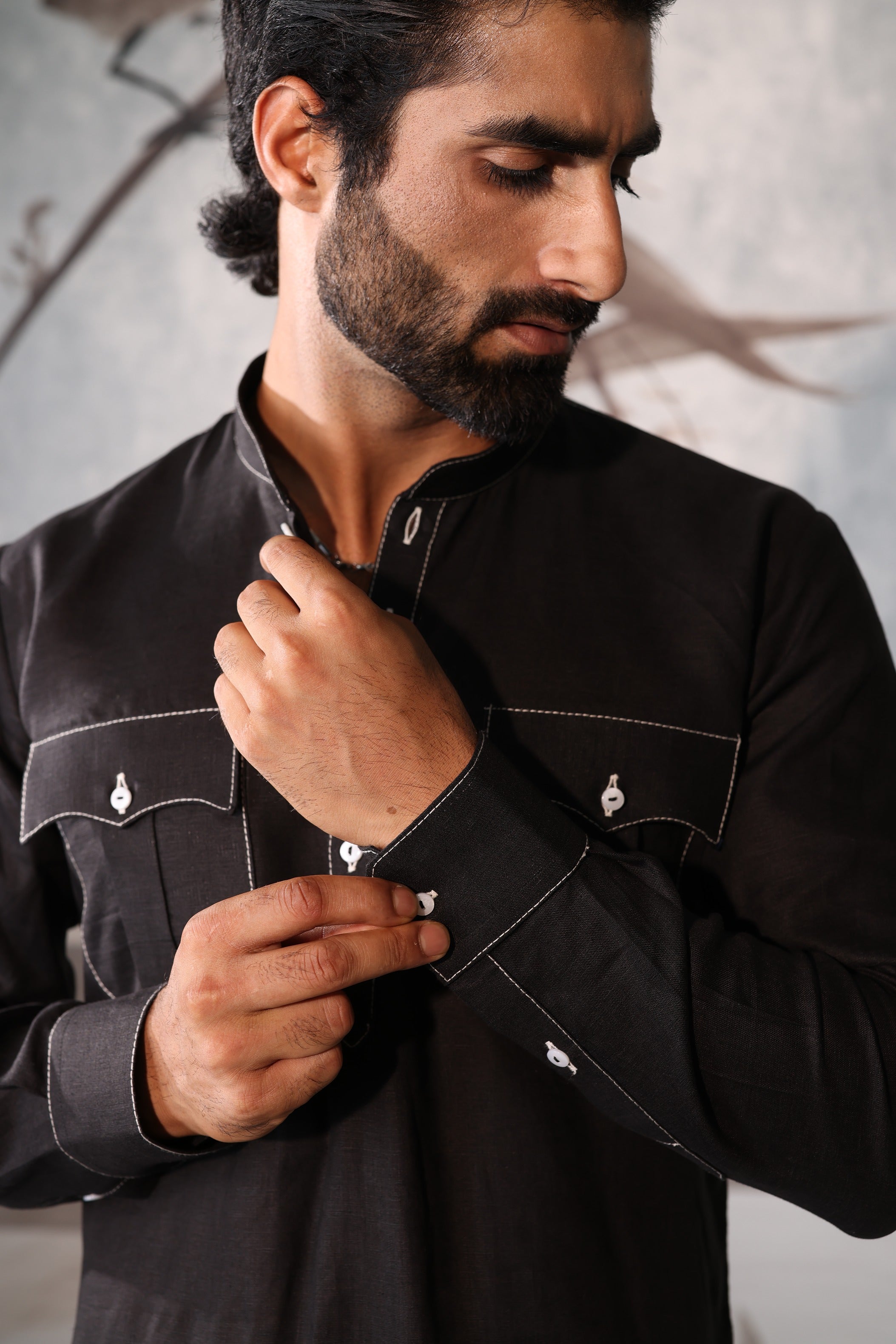 Man adjusting his black shirt against a neutral background