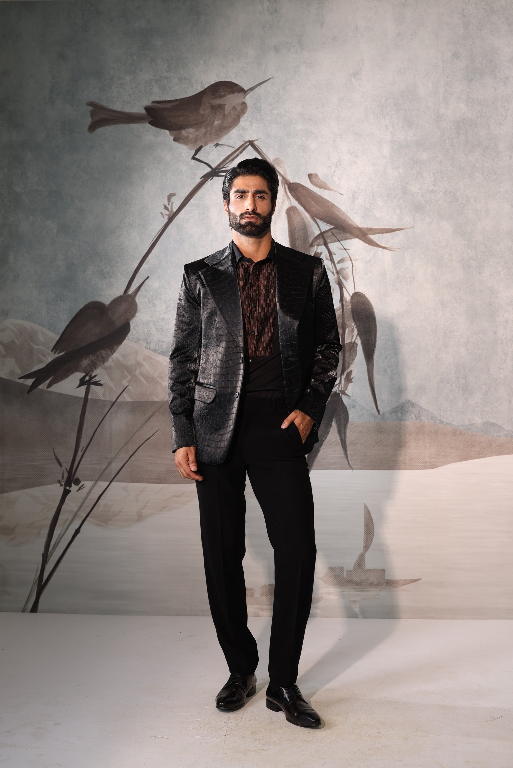 Man in a suit standing in front of a wall with bird artwork