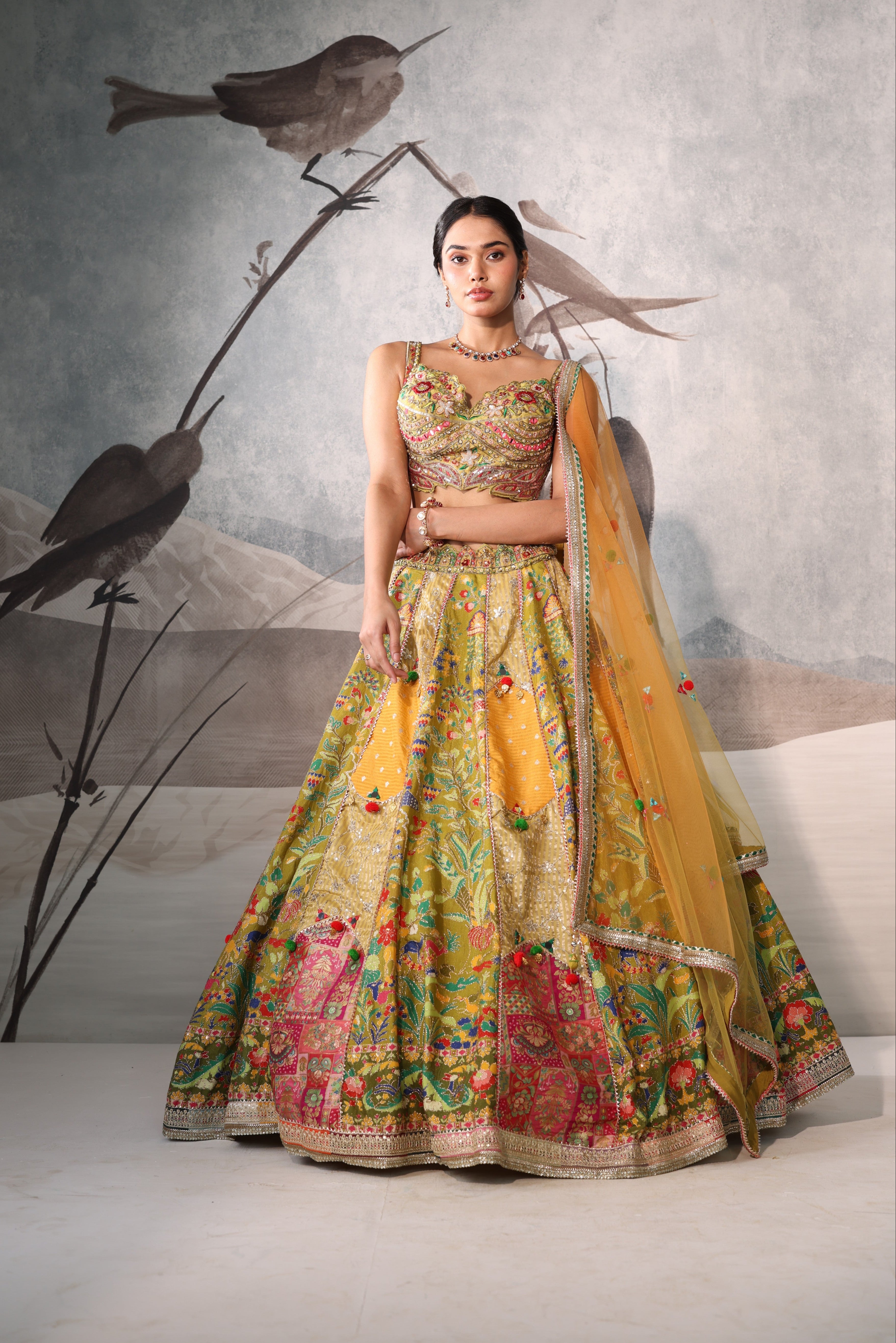 Woman in a colorful traditional outfit with birds on a branch in the background