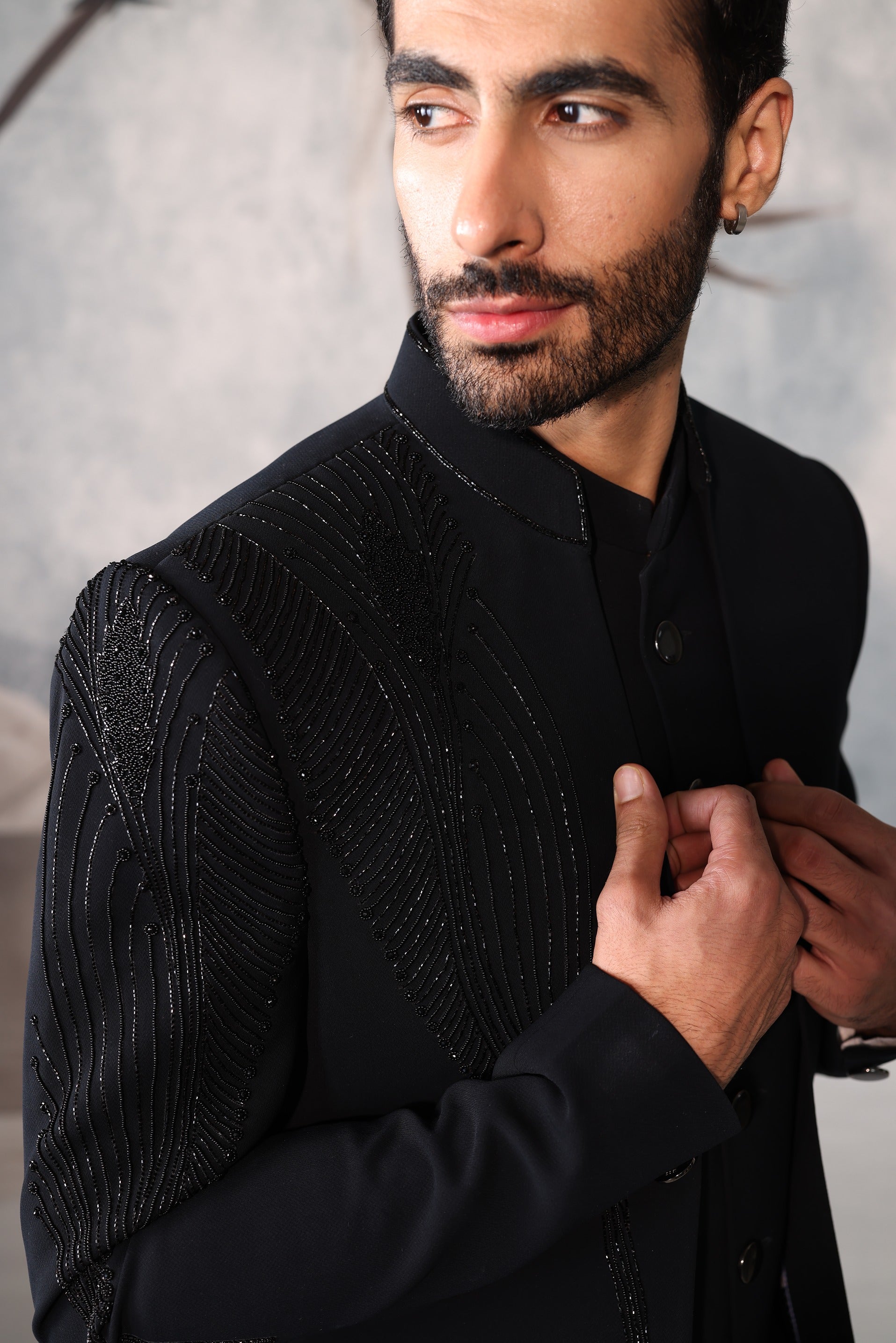 Man wearing a black textured sweater against a neutral background