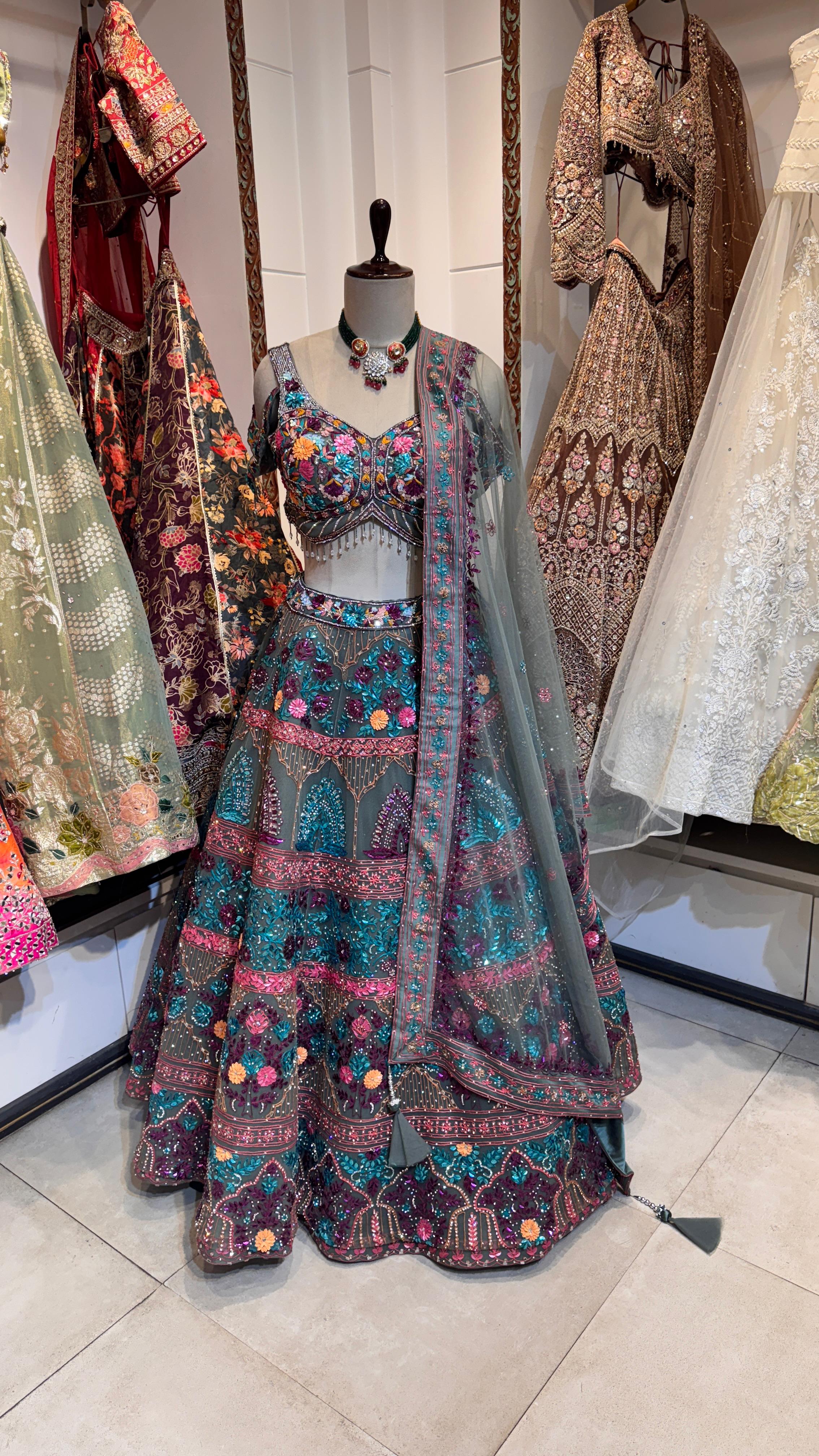 A mannequin displaying a green lehenga with multicolor embroidery and a dupatta.
