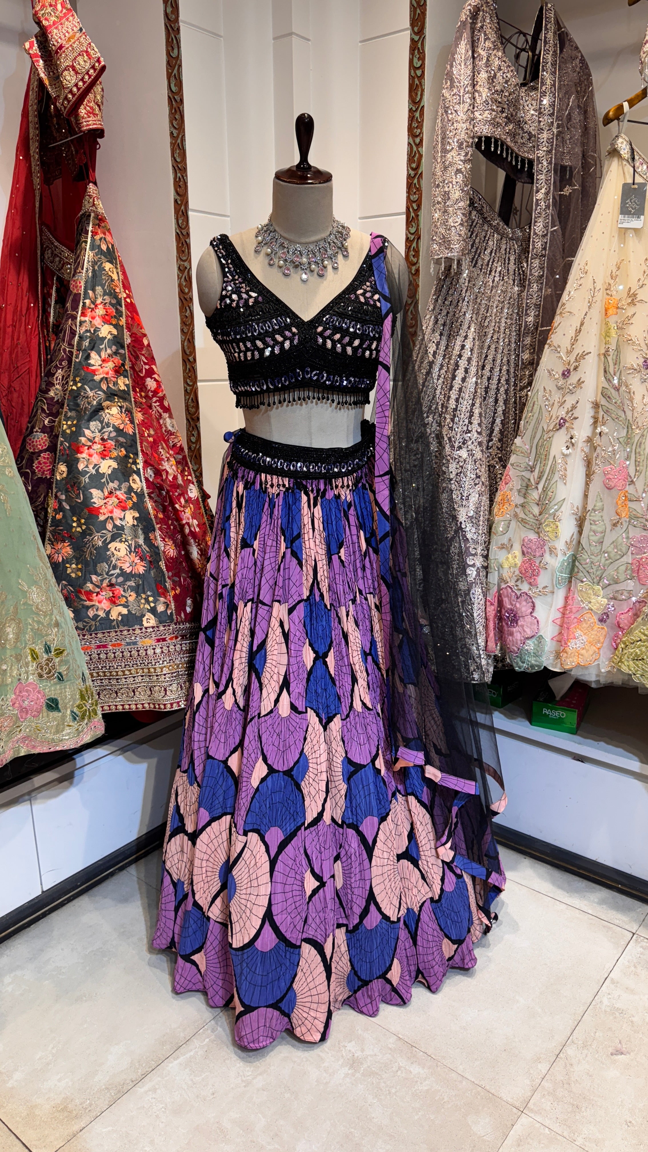 A traditional Indian lehenga featuring a purple zig-zag pattern, displayed with a matching blouse and dupatta.
