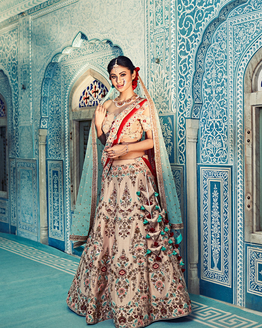 Mouni roy in a floral saree standing in a decorated room with blue and white walls.