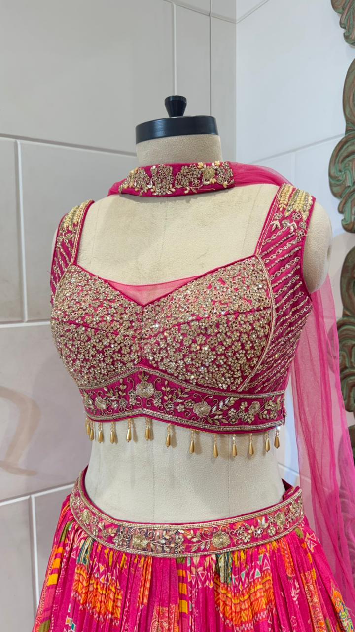 Traditional pink and gold embroidered blouse on a mannequin with a white tiled wall background